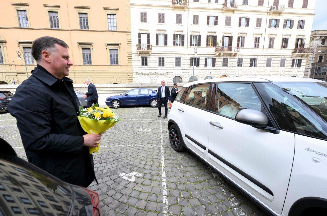 Een politieman brengt het boeket met gele bloemen naar de paus in de wagen.
