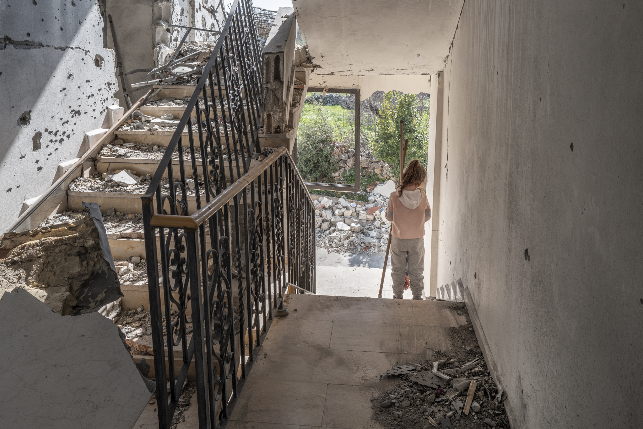 Het verwoest dorp Al Qaouzah. Een meisje loopt op de trappen van wat ooit haar huis was. Het verwoest dorp Al Qaouzah. Een meisje loopt op de trappen van een verwoest huis.