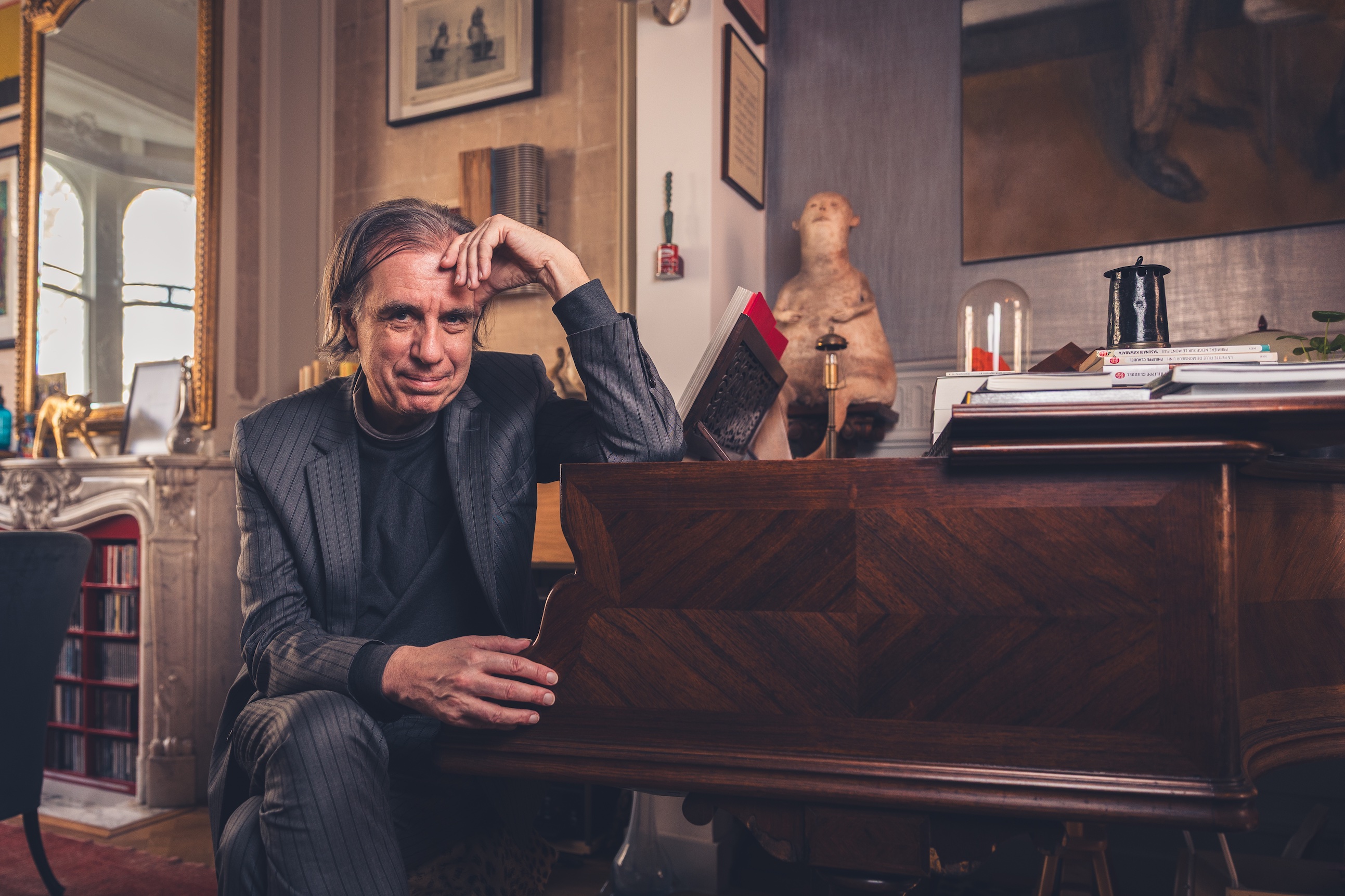 Dirk De Wachter, 'psychiater van het vaderland', schreef een boek over wachten als levenshouding. Dirk De Wachter met elleboog leunend op zijn piano - bruinkleurig interieur.