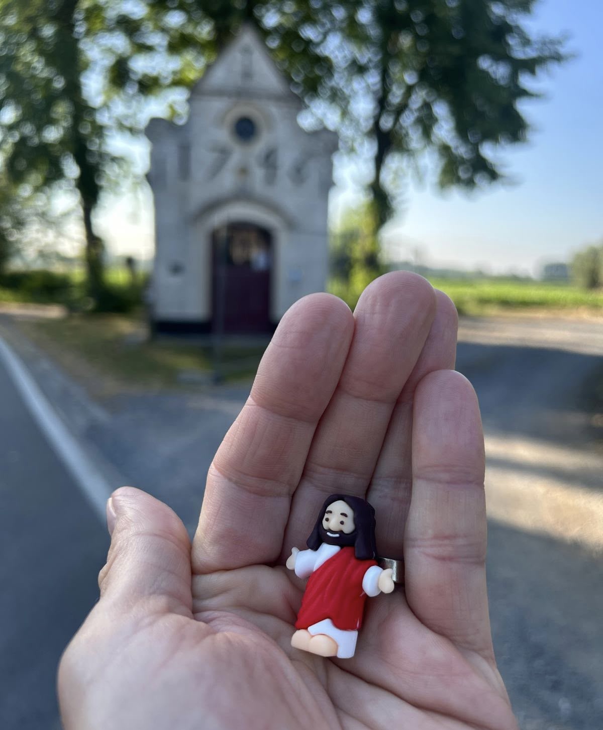 Jezus poppetje in de hand van Aniko. Ze nadert een kapelletje.