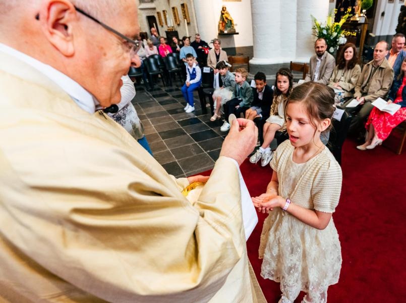 Eerste communie 2026 Een eerste communie waarbij een kind voor het eerst de hostie ontvangt in de kerk.