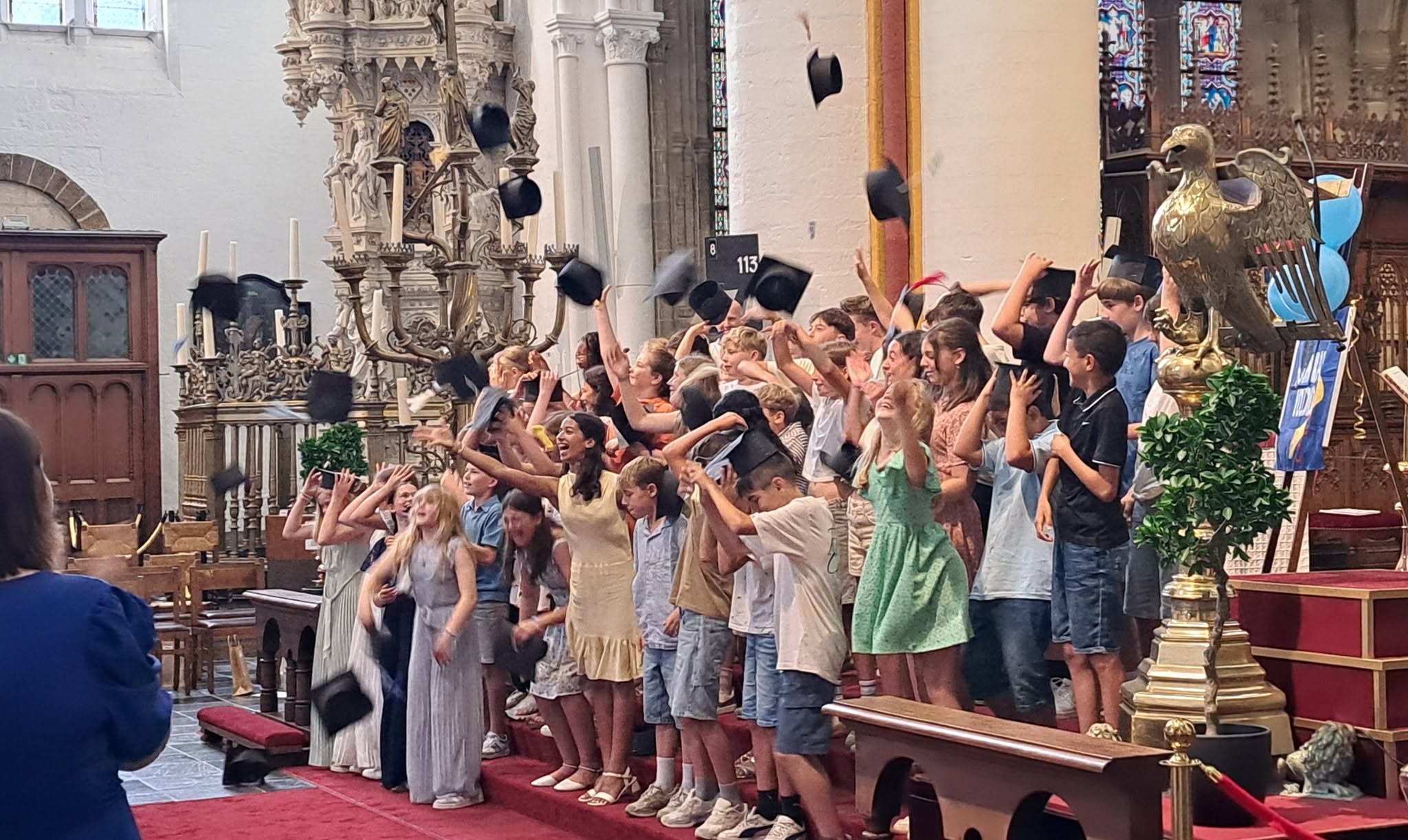 Proclamaties leerlingen in koele kerken Een groep leerlingen die hun baret de lucht in gooien tijdens een proclamatie of afstudeerplechtigheid in een kerk.