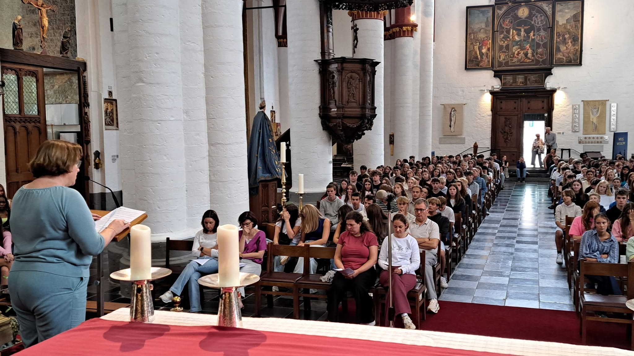 Middelbare scholen Zoutleeuw maken een gelovige start Een kerkinterieur tijdens een viering (een schoolstart), met banken vol mensen en een preekstoel.