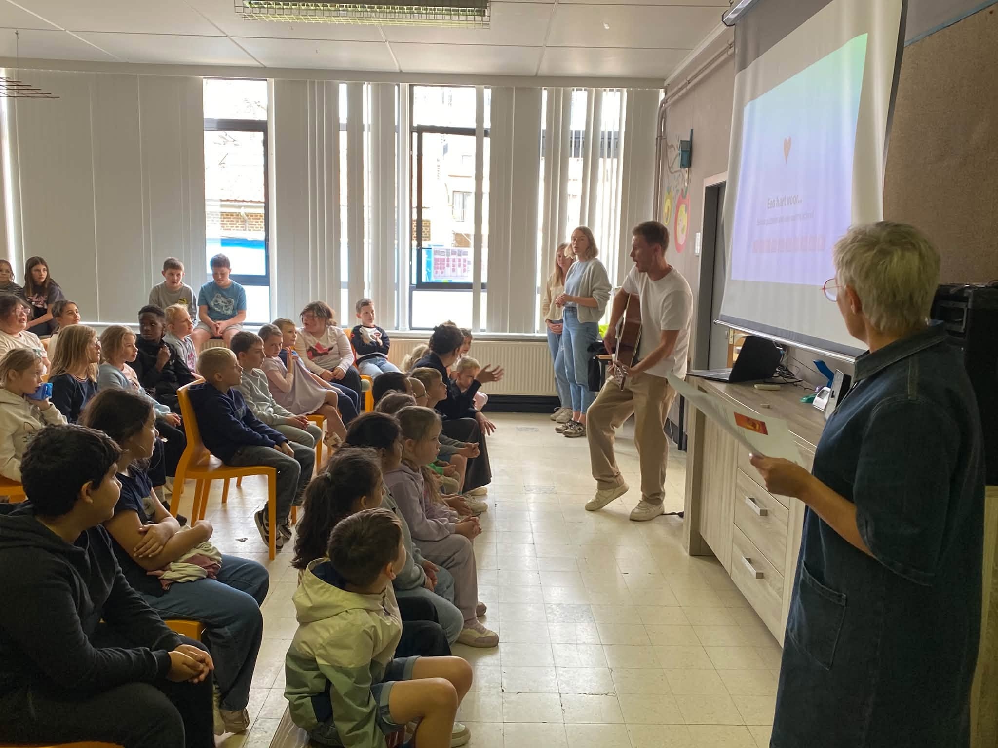 Een klaslokaal of presentatieruimte waar een groep kinderen of leerlingen naar een spreker of presentatie luistert.
