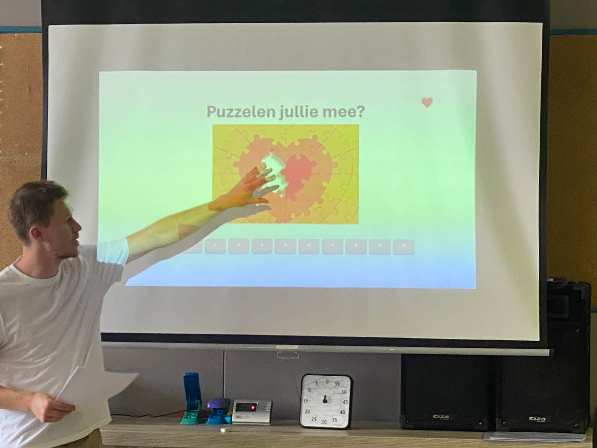 Een persoon die een presentatie geeft voor een scherm waarop een thermografische afbeelding of hittekaart (warmtebeeld) te zien is.