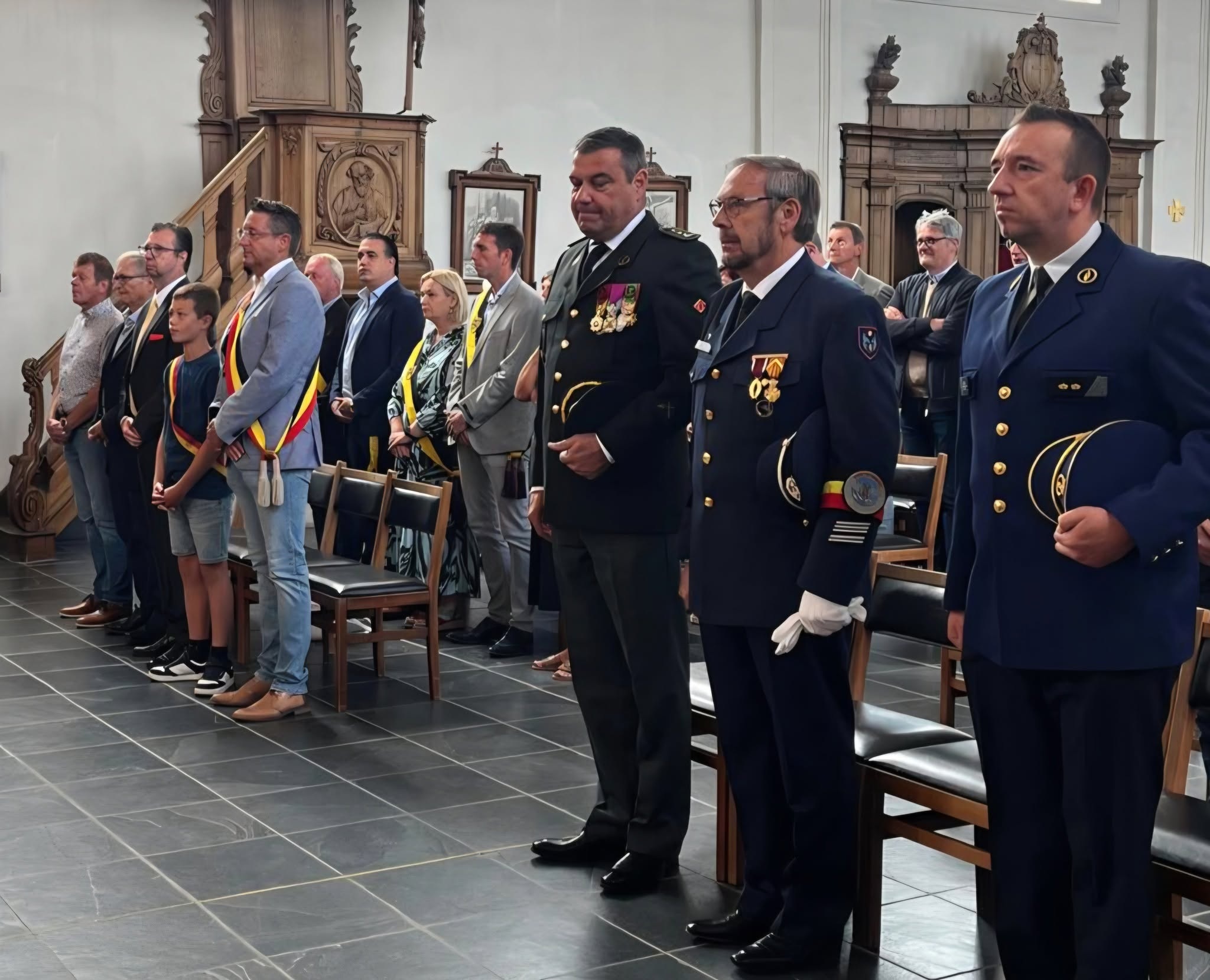 Te Deum-viering op Nationale Feestdag Een plechtige bijeenkomst in een kerk waar onder andere militairen, veteranen en vertegenwoordigers in uniform of formele kleding (zoals dragers van een sjerp en onderscheidingen) opgesteld staan.