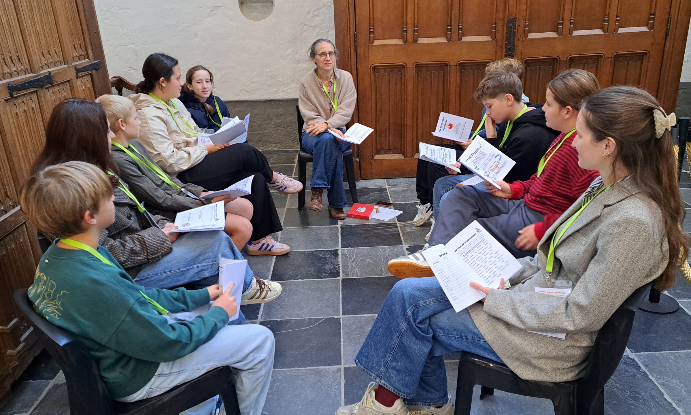 Samen op weg naar het vormsel Een groep mensen die in een cirkel bij elkaar zit, vermoedelijk tijdens een groepsgesprek, bezinning of workshop waarbij ze papieren of documenten vasthouden.