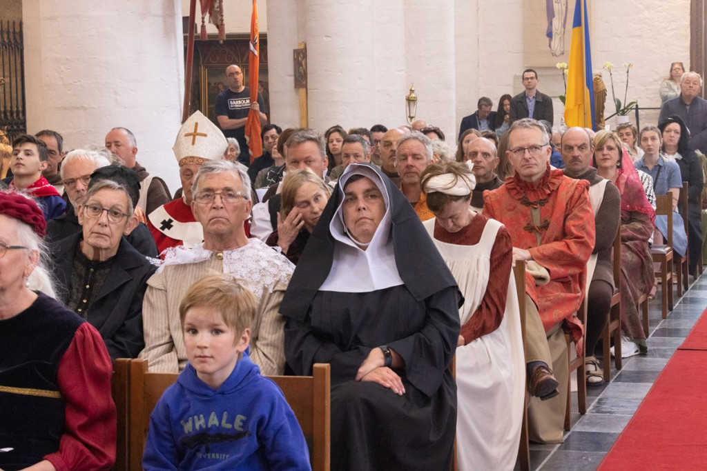 Figuranten die mee oplopen in de processie volgen de mis in hun historische kledij.