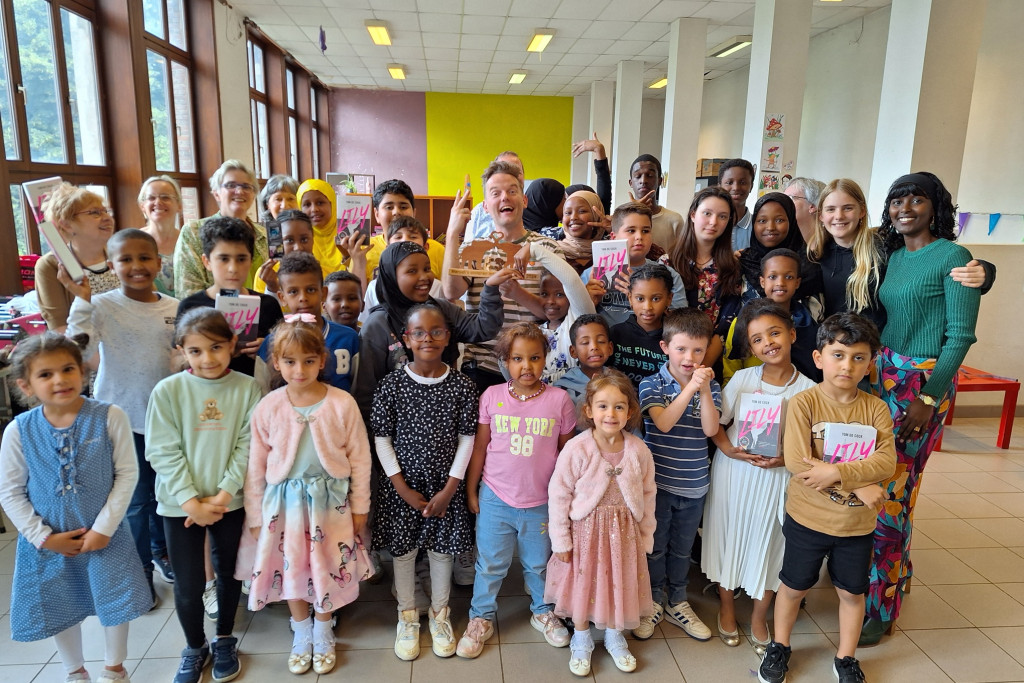 Tom De Cock (midden) ontving de inspiratieprijs uit handen van Ayan Mohamud Yusuf (rechts) voor zijn bijdrage aan de leescultuur van anderstalige kinderen.