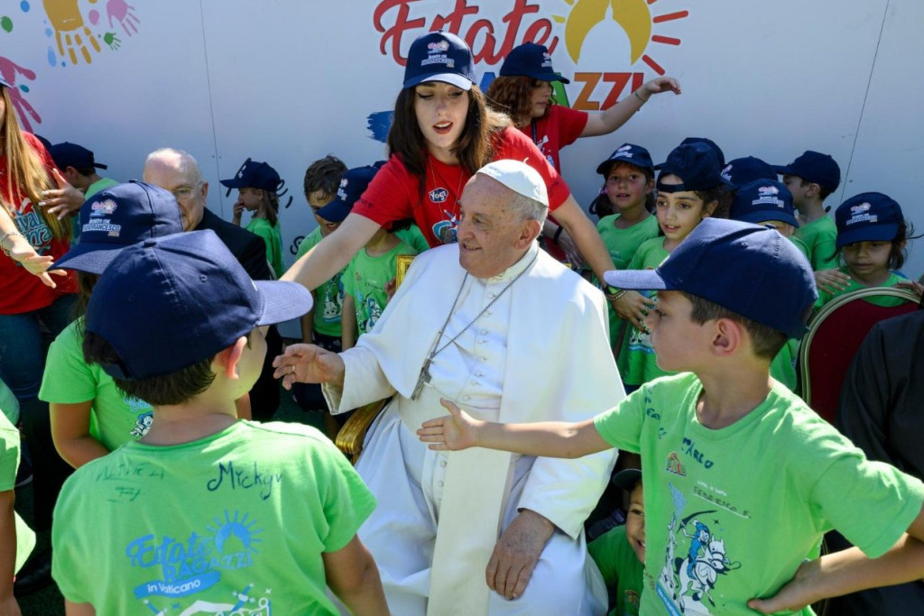 Paus Franciscus omringd door kinderen in groene T-shirts op het zomerkamp van het Vaticaan.