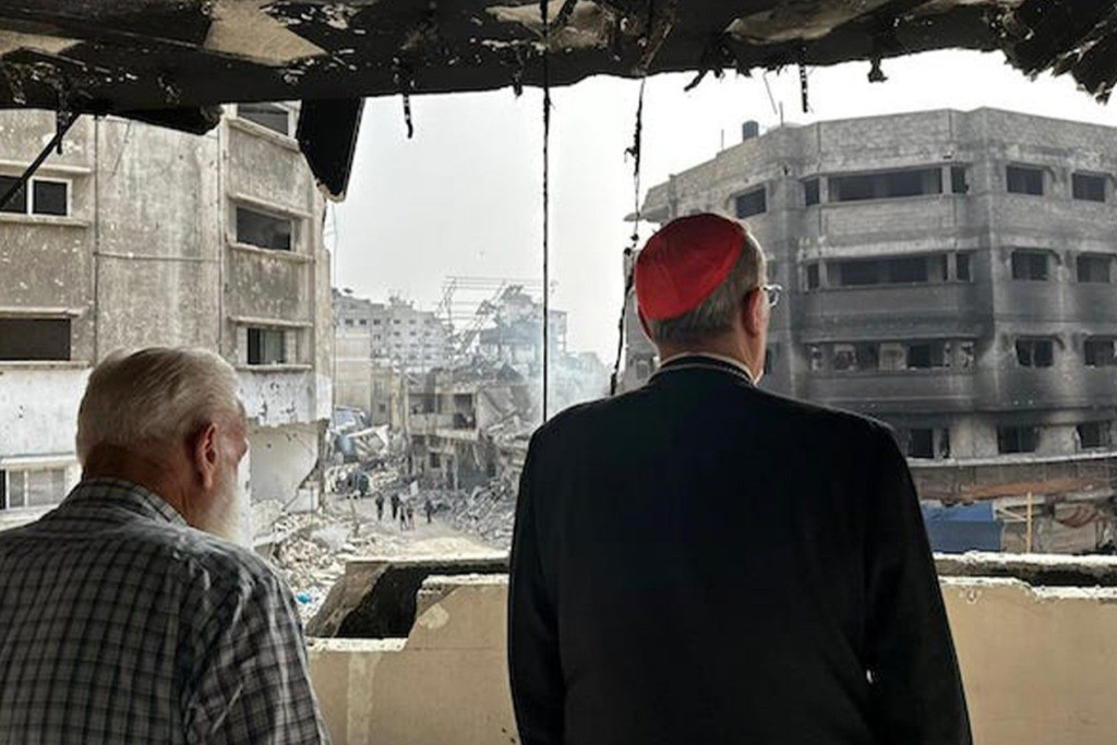 Kardinaal Pizzaballa (van op de rug) bekijkt de vernieling in de straten van Gaza, vanuit een kapot geschoten gebouw.