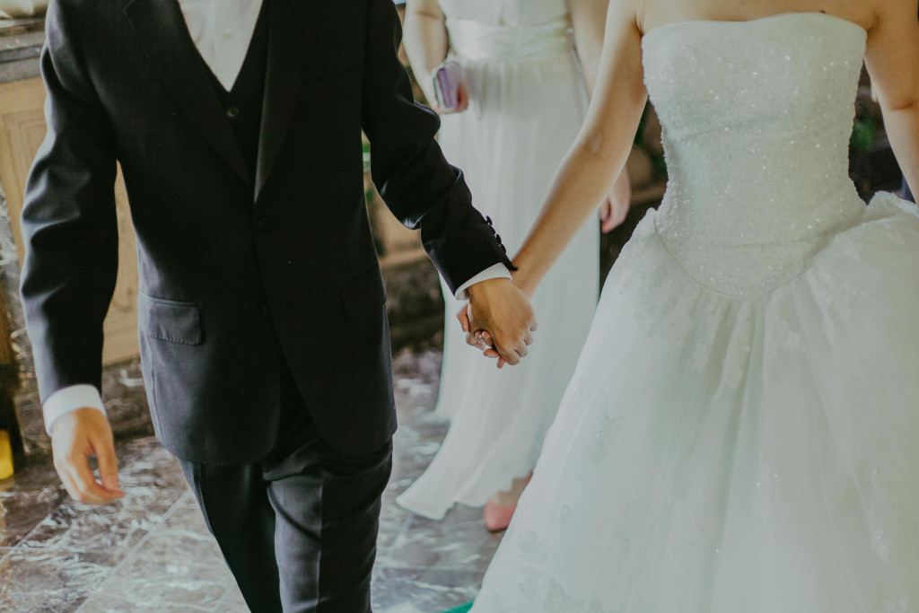 Man en vrouw in trouwkledij houden handen vast en zijn op weg naar het altaar.