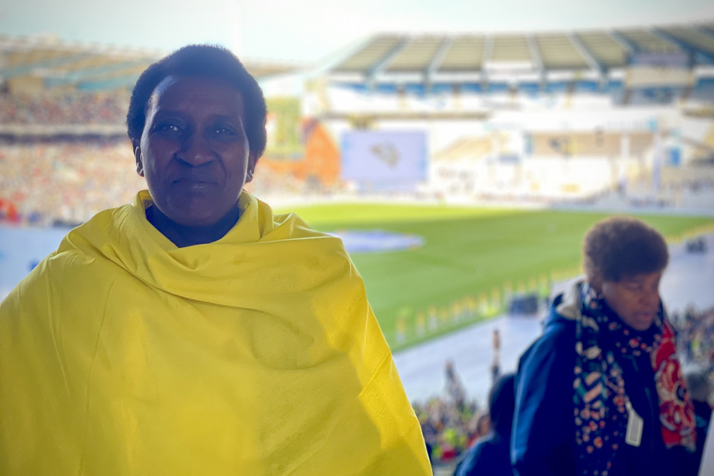 Een vrouw in Vaticaanse kleuren gehuld poseert voor de foto in het Koning Boudewijnstadion, vlak voor de mis met de paus begint.
