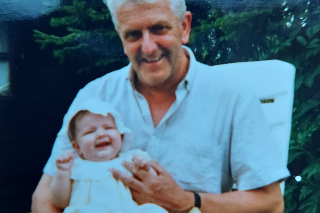 Een baby zit lachend op de schoot van haar opa.