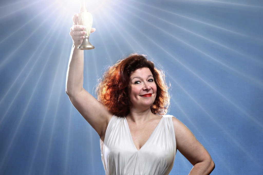 Veerle Malschaert straalt op de affiche van haar show 'Verlicht mij'. Veerle Malschaert in witte jurk met lichtfakkel in de hand (lijkend op het Vrijheidsbeeld).