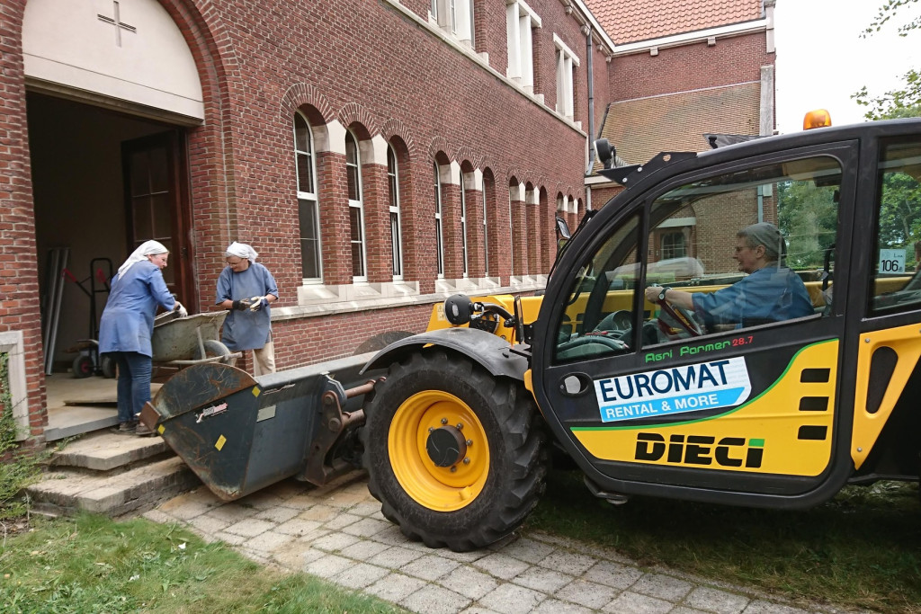 Twee zusters sjouwen met een kruiwagen, de derde bestuurt een zware machine..