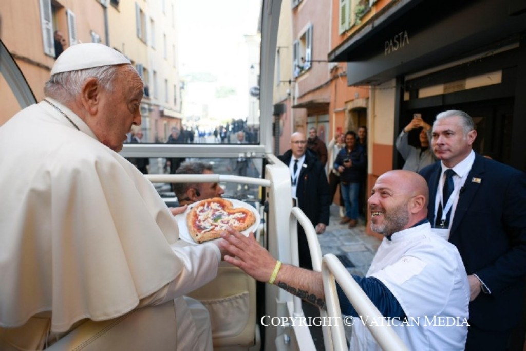'Corsica houdt van u', verzekert deze pizzabakker de paus bij zijn bezoek in Ajaccio. Pizzabakker overhandigt paus in pausmobiel een pizza in de vorm van een hart.