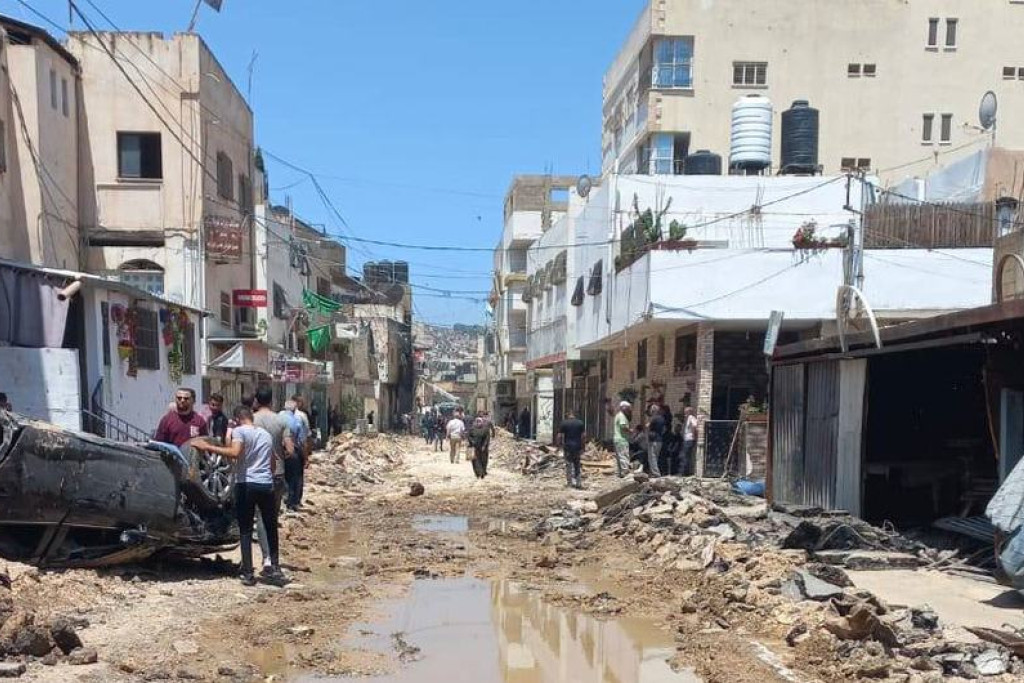 Zicht op een straat in het vluchtelingenkamp van Jenin, waar veel vernieling is aangebracht. Een auto ligt op de kop.