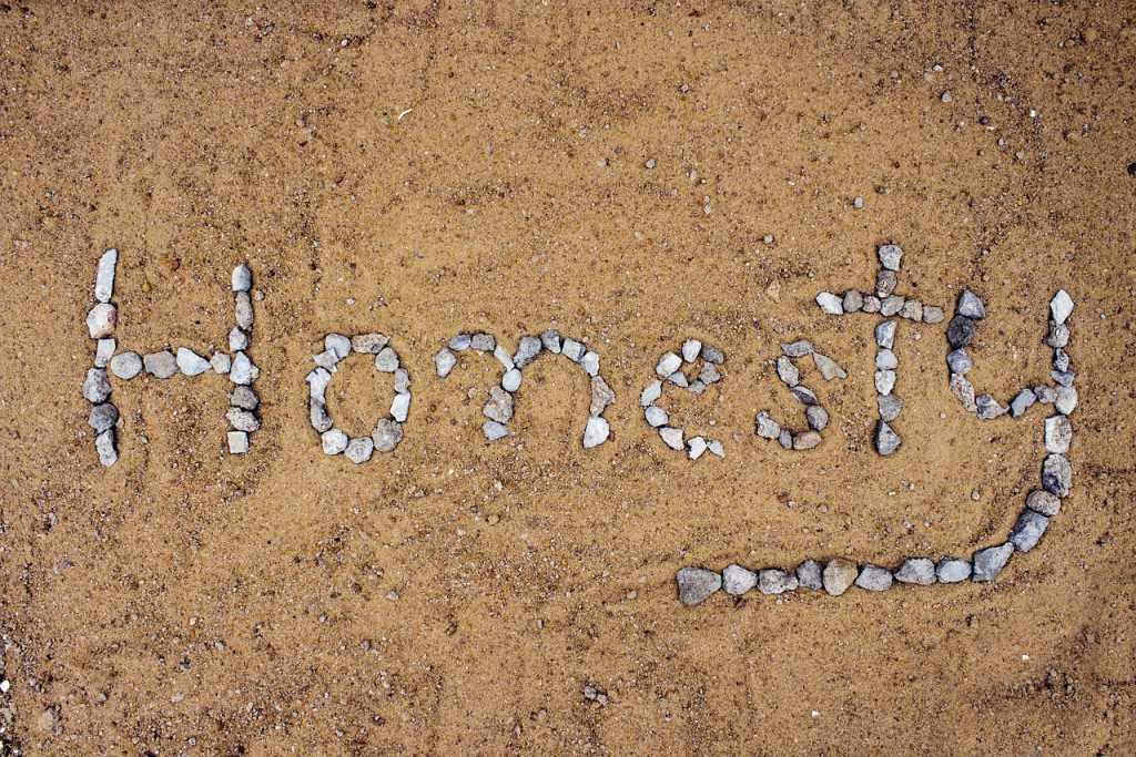 In het zand liggen kiezelstenen in de vorm van het woord 'honesty' of 'eerlijkheid'.
