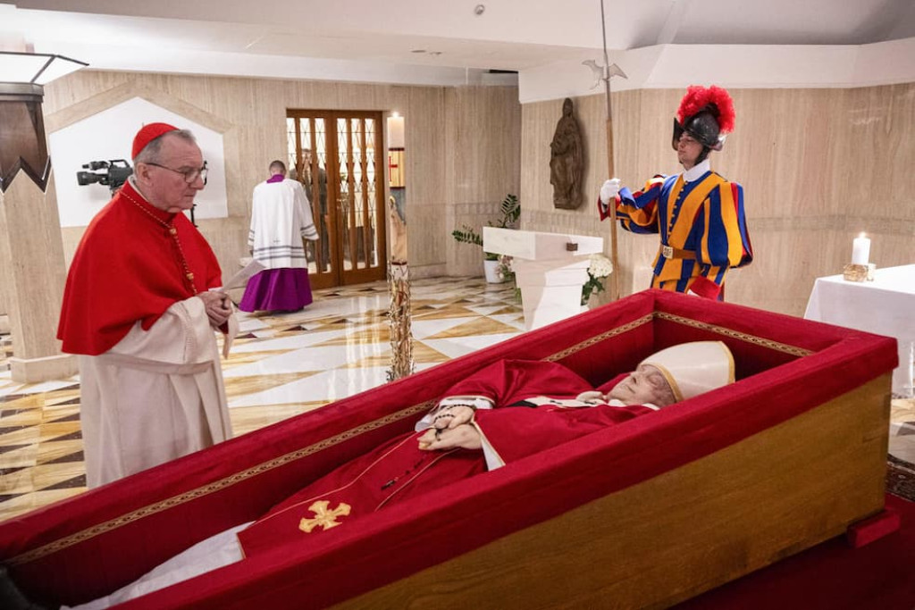 Paus Franciscus ligt opgebaard in zijn privékapel in de Casa Santa Marta, gekleed in een rood gewaad en een witte mijter, met een rozenkrans in de hand