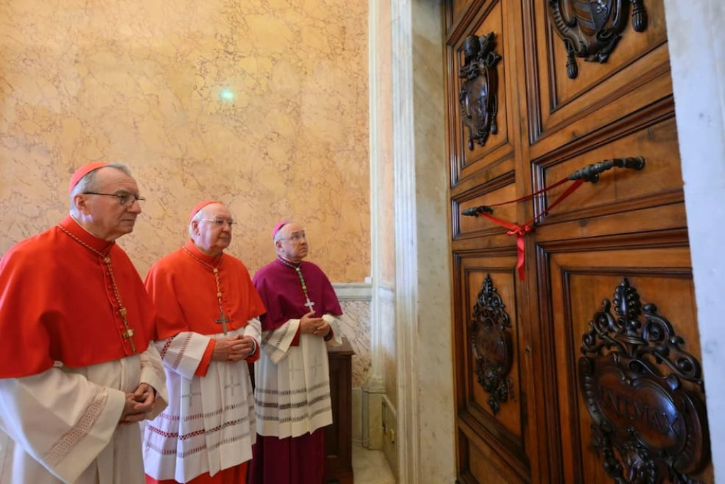 Kardinaal Kevin Farrell (midden) verzegelt op maandag 21 april 2025 het pauselijk appartement in het Apostolisch Paleis samen met staatssecretaris van het Vaticaan kardinaal Pietro Parolin en aartsbisschop Edgar Peña Parra 