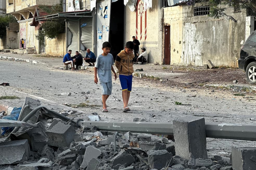 Twee Palestijnse kinderen lopen door het puin van hun wijk in Khan Yunis, in het zuiden van de Gazastrook, na nachtelijke Israëlische bombardementen op 15 mei 2025