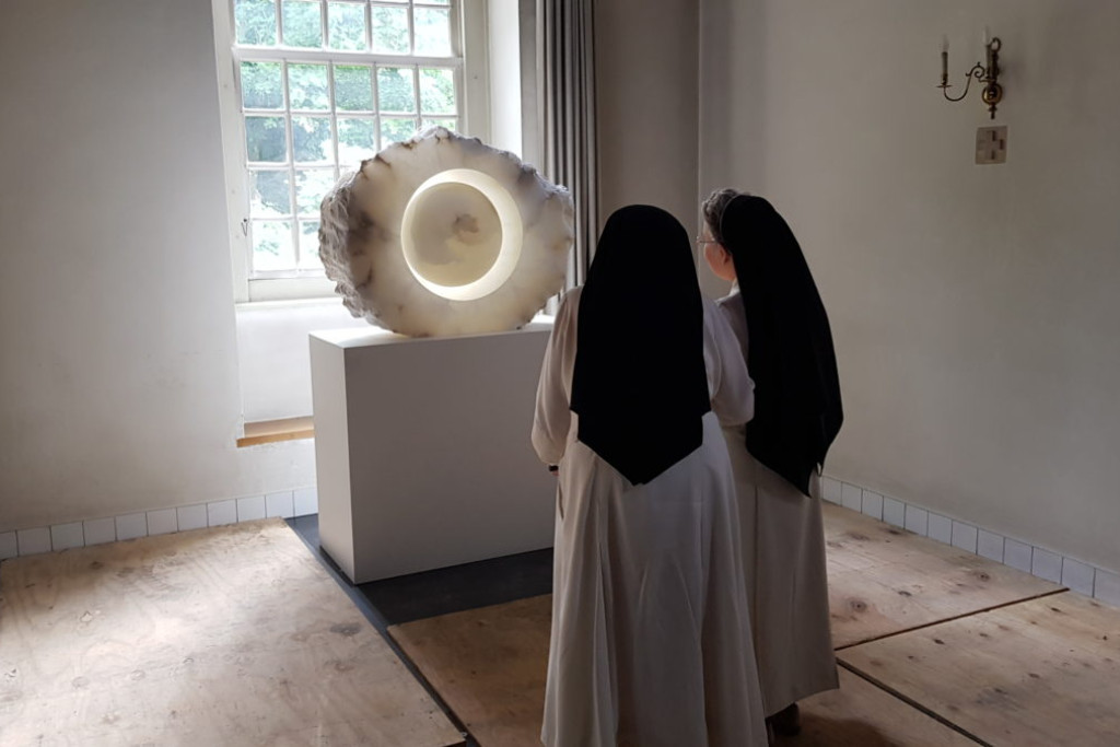 Twee norbertinessen van Catharinadal kijken naar een kunstwerk op de biënnale h3h van 2023. Twee norbertinessen (zwarte kap, wit kleed) kijken naar een kunstwerk op de biënnale h3h van 2023.