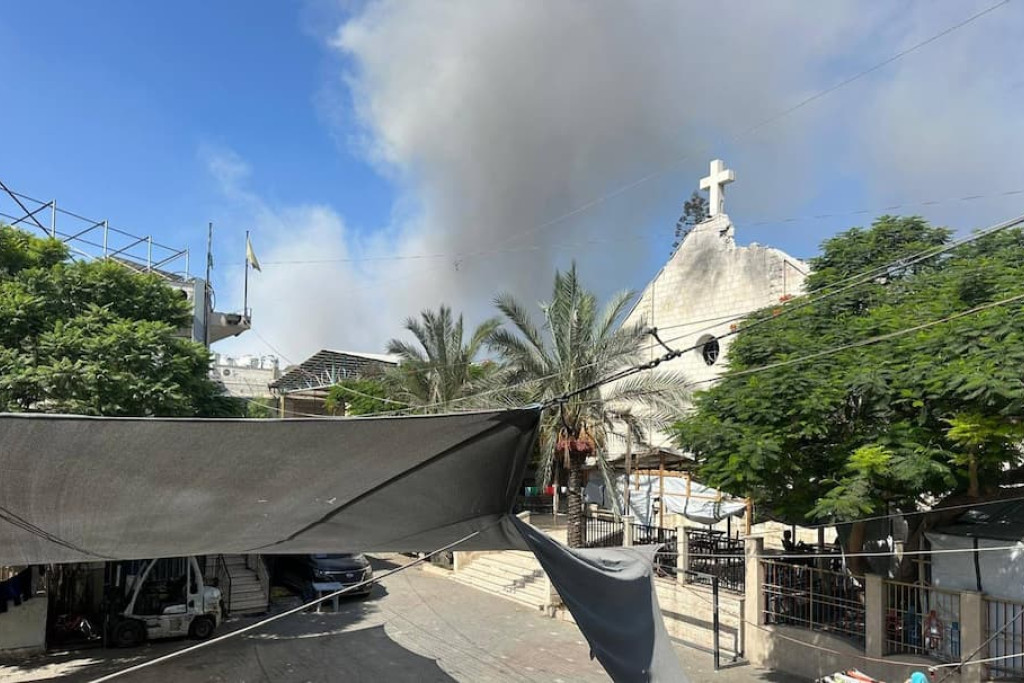 Heilige Familiekerk in Gaza-Stad op 26 augustus met rookwolken van bombardementen op de achtergrond