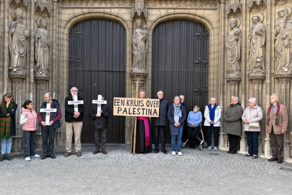 Bisschop Bonny op Goede Vrijdag, staat voor de kathedraal met medestanders en een kruis met daarop de tekst 'Een kruis over Palestina'.