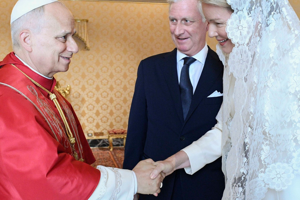 Koningin Mathilde schudt paus Leo XIV de hand. Daarachter staat koning Filip.