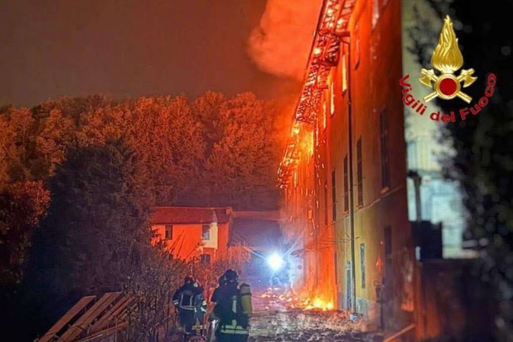 Goeiend rode vlammen schieten uit alle ramen van het kloostergebouw tegen de nachtelijke hemel.
