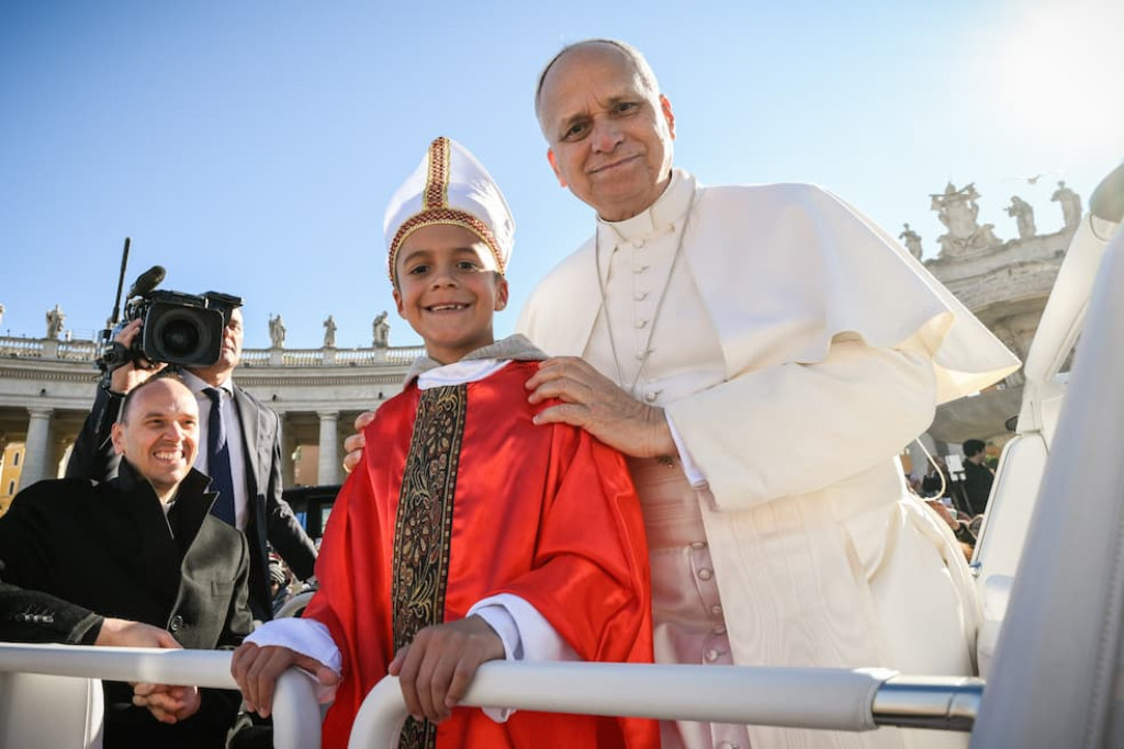 Paus Leo XIV en zijn jonge evenbeeld hebben zichtbaar plezier in hun gezamenlijke fotomoment op het Sint-Pietersplein op 23 november 2025