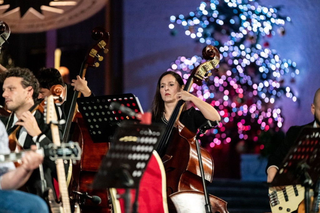 Vrouw met cello en op de achtergrond de lichtjes van een kerstboom