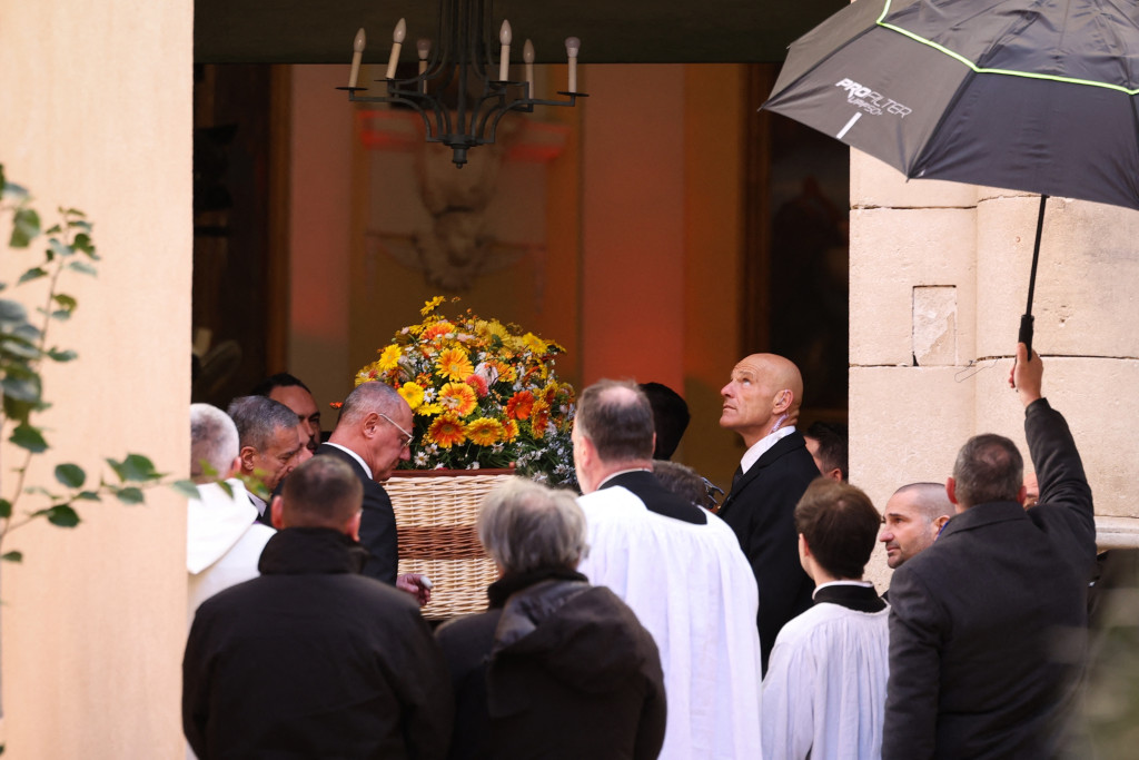 De rieten kist wordt de kerk buitengedragen.