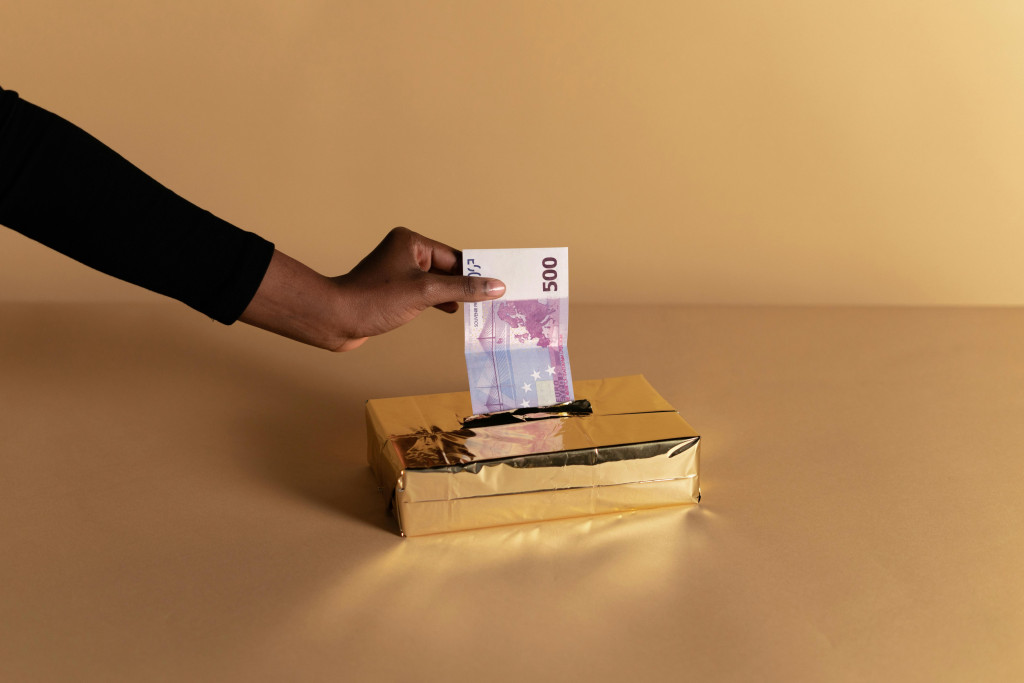 Hand steekt bankbiljet in gleuf