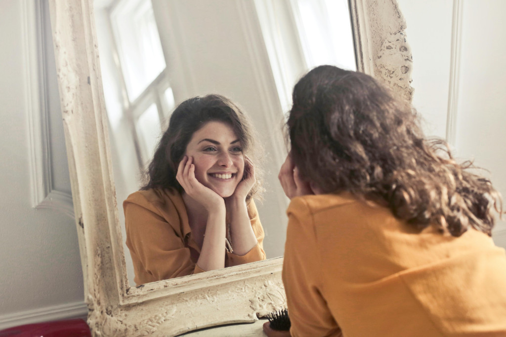Vrouw kijkt lachend in de spiegel.