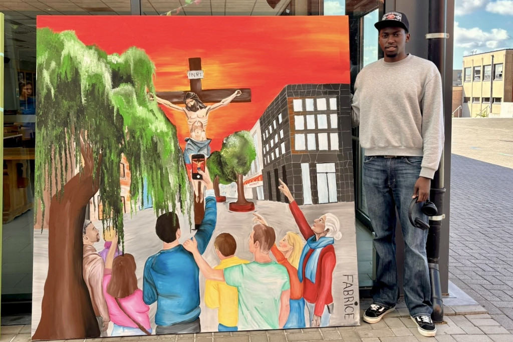 Fabrice Rugwizangoga bij zijn allereerste schilderij. Fabrice poseert naast zijn schilderij: de kruisiging van Christus tegen een rode achtergrond. Op de voorgrond mensen die staan te kijken, te wijzen en te filmen met de smartphone.