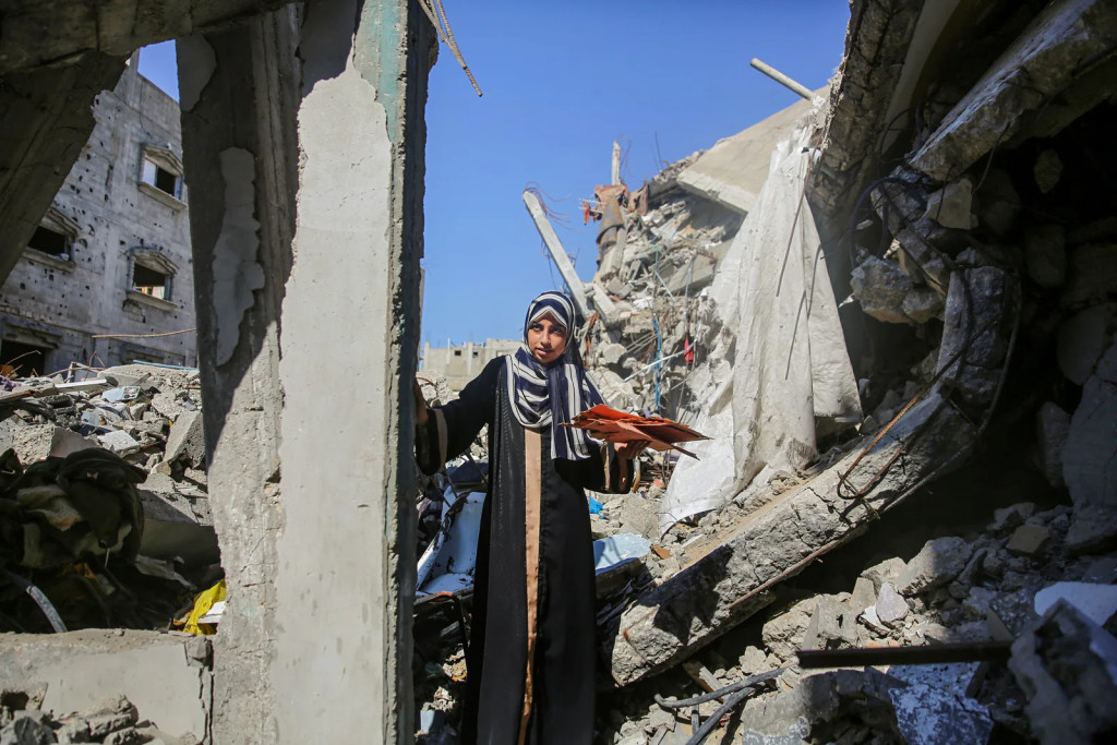 Israël bezet nog steeds de helft en meer van het grondgebied van Gaza. In het bezette deel wordt elk gebouw met de grond gelijk gemaakt. Een vrouw loopt door puin in Gaza.