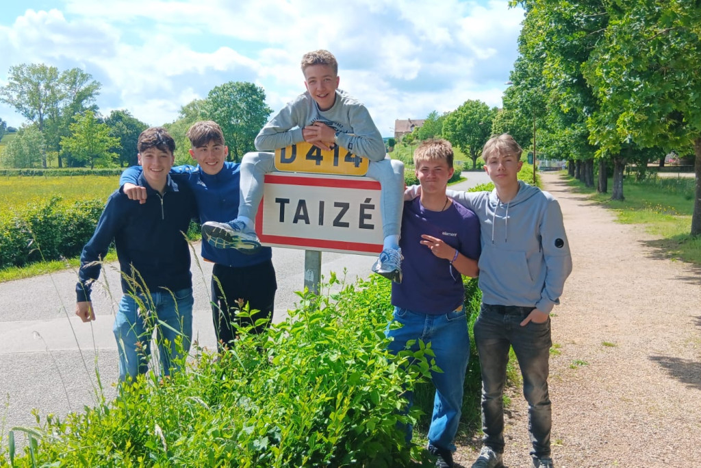 Vijf leerlingen van het VHSI in Brugge poseren rond het plaatsnaambord van Taizé, een dorpje in de Bourgogne waar de gelijknamige oecumenische broedergemeenschap gevestigd is..