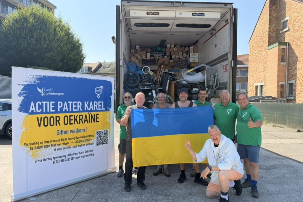 Leden van STAM-Oud Scouts Grimbergen en pater Karel (rechts onderaan) laden de truck met hulpgoederen in.