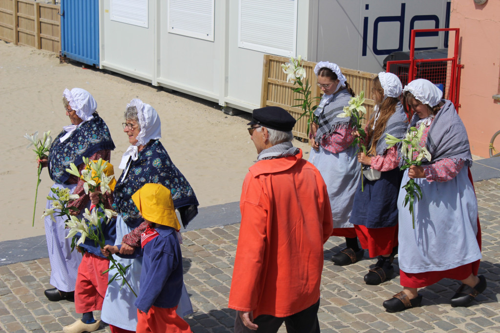 Vrouwen in traditionele klederdracht brengen bloemen aan. Zeezegening Blankenberge