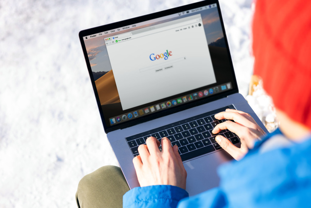 Persoon met rode muts tikt zoekterm in op laptop via Google.