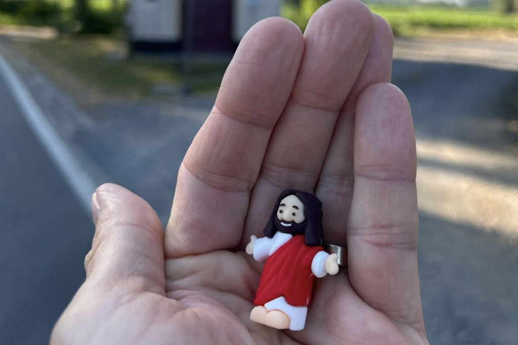 Jezus poppetje in de hand van Aniko. Ze nadert een kapelletje.
