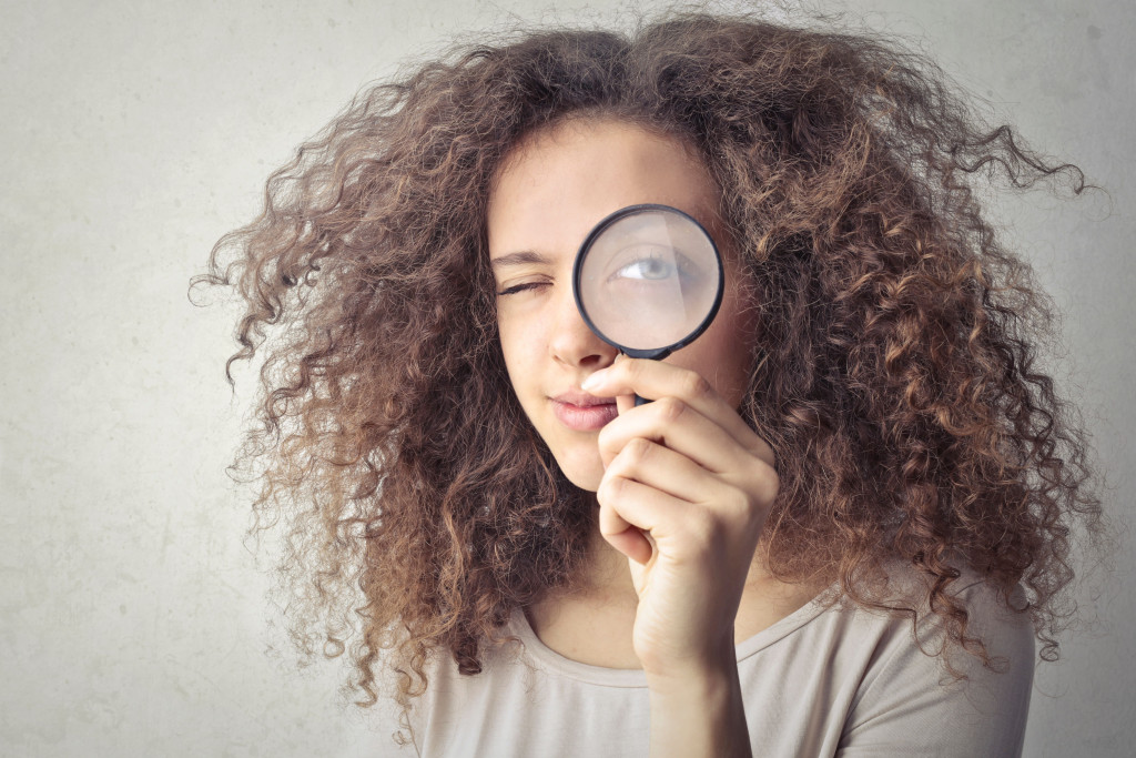 Vrouw kijkt door vergrootglas
