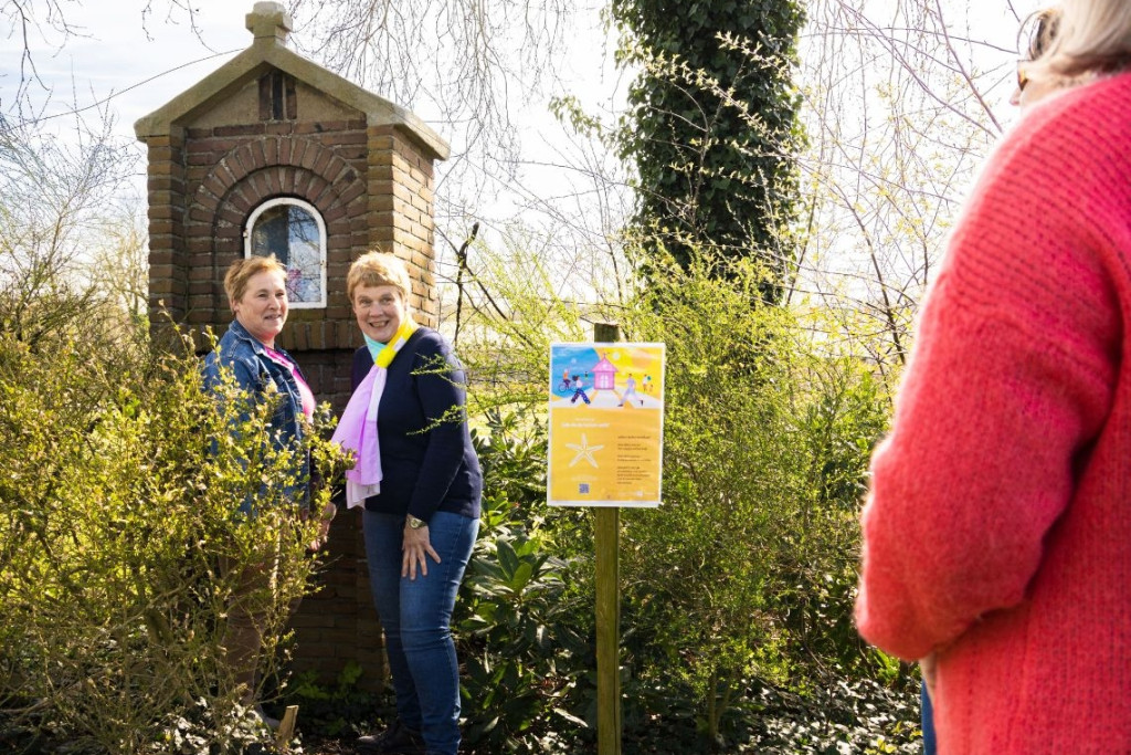 Bij een van de vele vertelkapellen in Meerle (Noorderkempen). Vrouwen poseren bij een 'vertelkapel', een Mariakapel met een bordje waarop je via een QR-code naar een verhaal kunt luisteren.