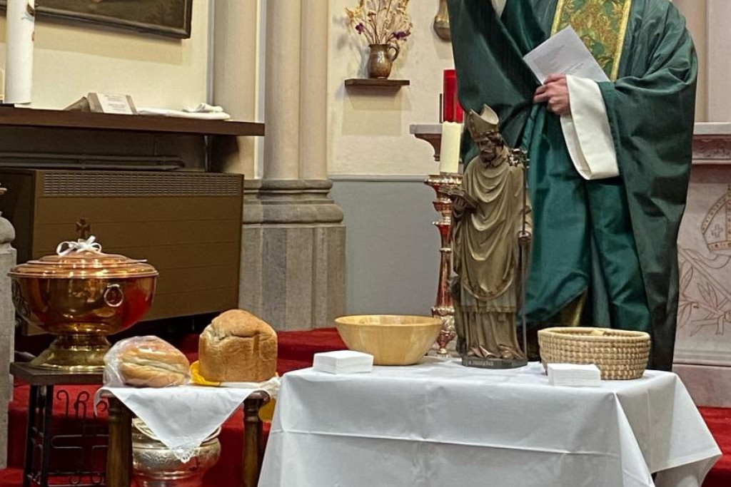 Een Sint-Hubertusviering met een traditionele broodzegening (en eventueel broodjeswijding) door een priester in een katholieke kerk.