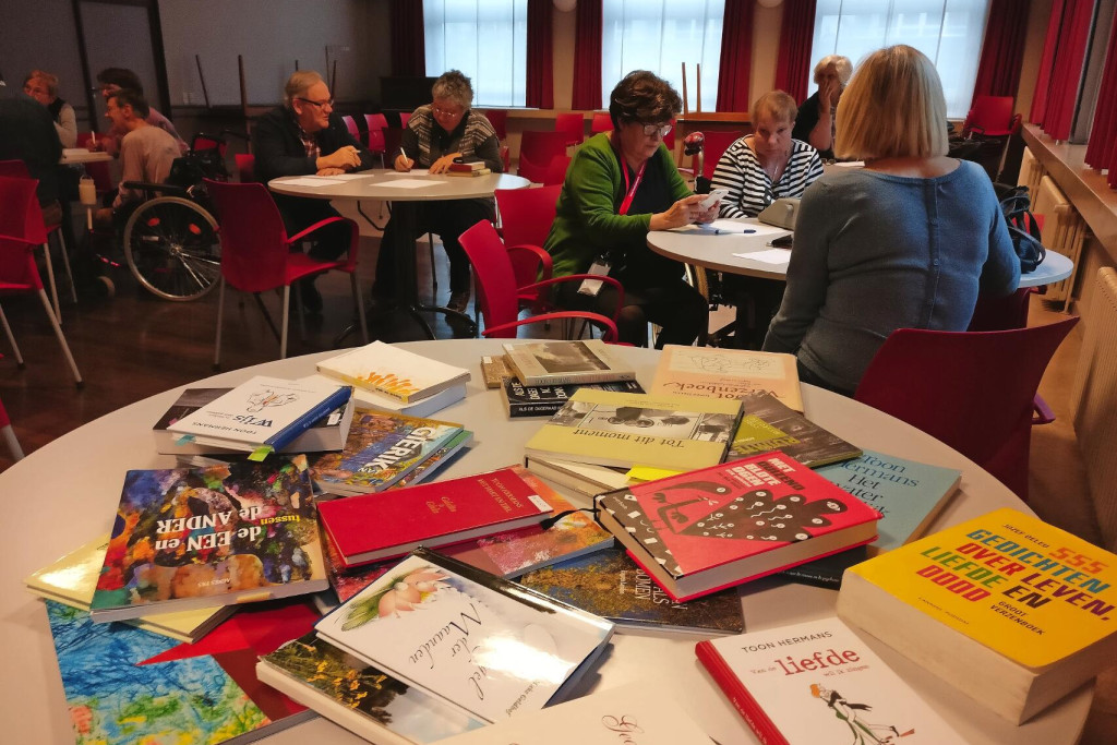 Twaalf chronisch zieke mensen en de begeleiders werken geconcentreerd aan hun gedichten. © Sien Wevers
