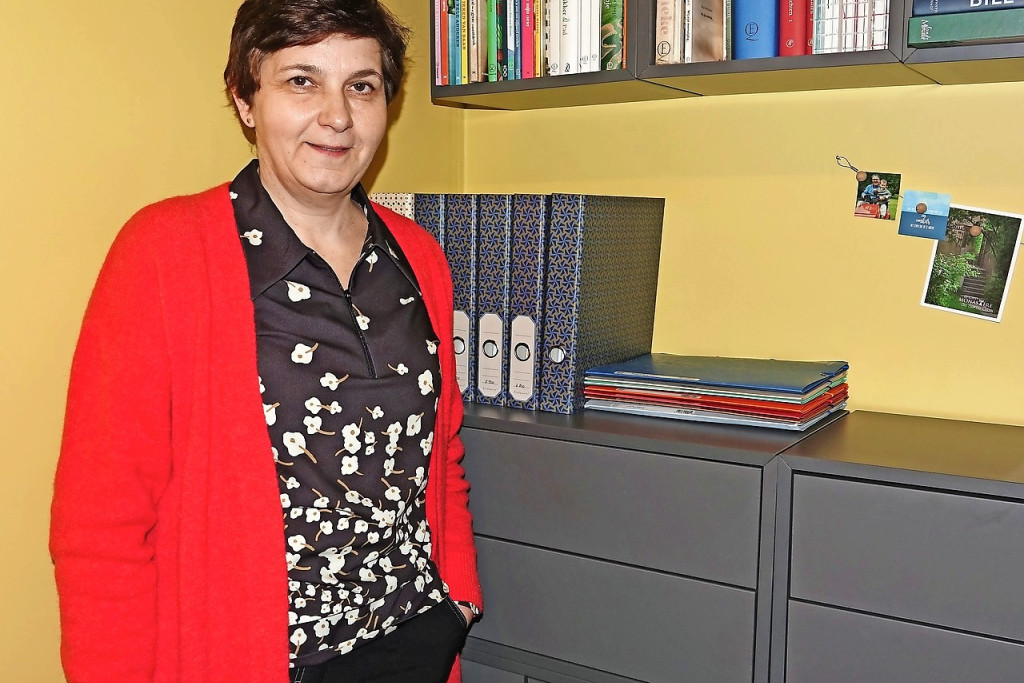 Petra Van den broeck voor een opgeruimde boekenkast met inbegrip van mappen om papieren op te bergen. © Bart Luykx