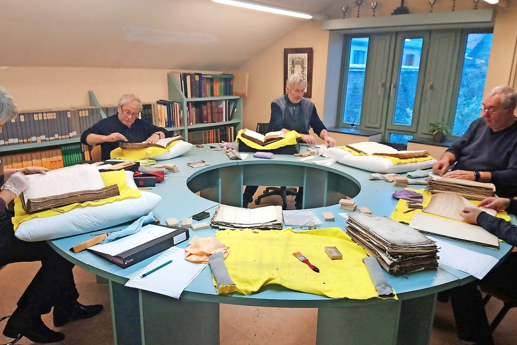 Blad voor blad reinigen vrijwilligers de aangeboden documenten. © Céline Decottignies
