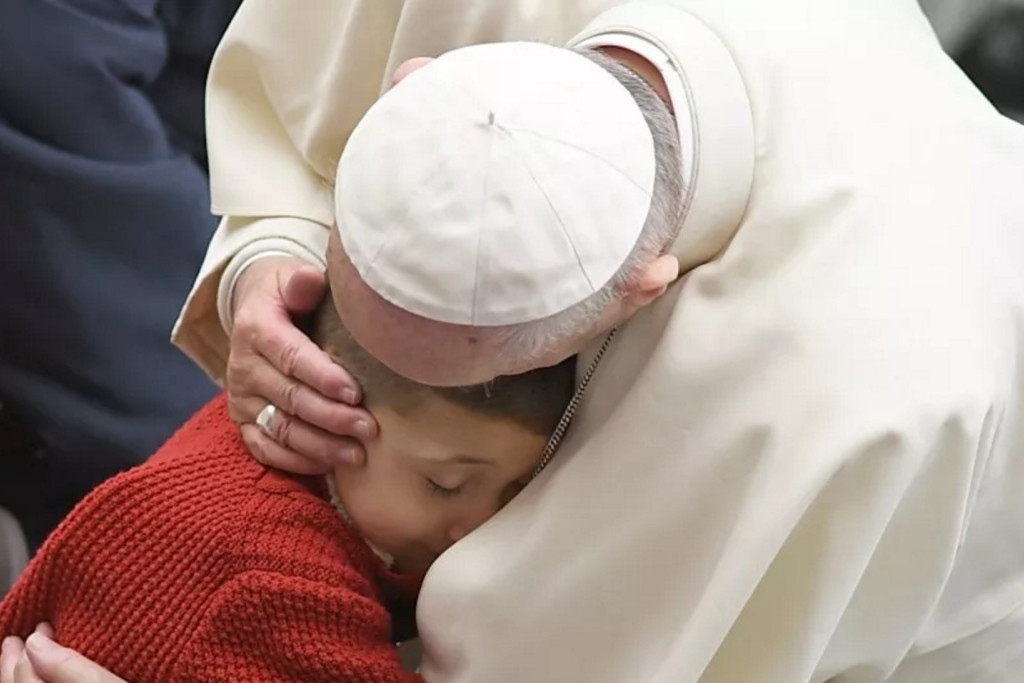 Paus Franciscus knuffelt een kind tijdens de algemene audiëntie